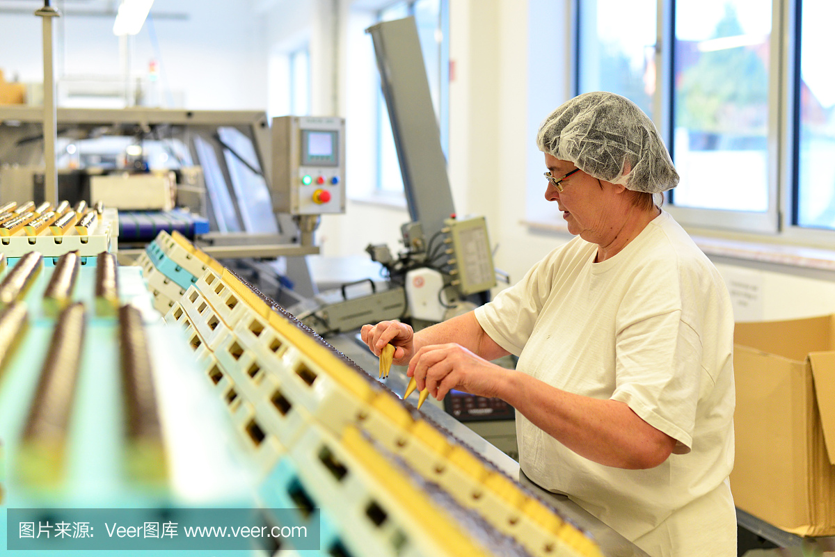 在一家为食品工业生产果仁糖的工厂里,妇女在装配线上工作
